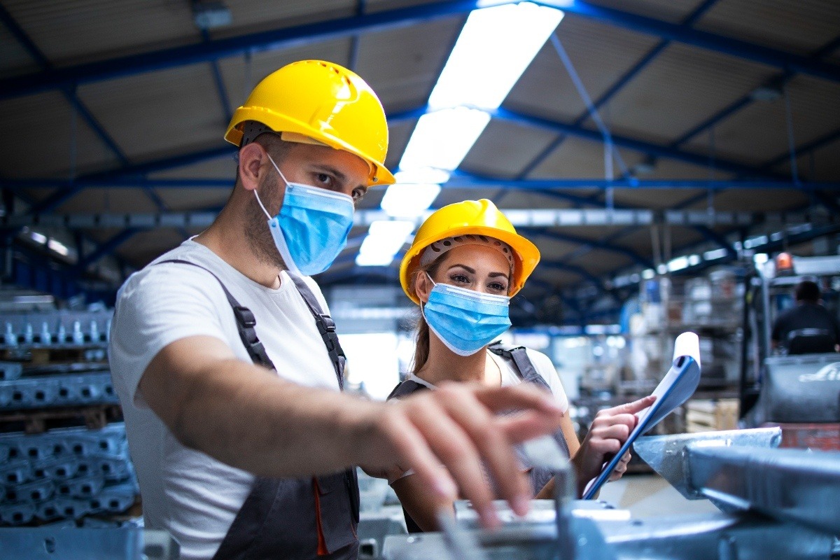 industrial-workers-with-face-masks-protected-against-corona-virus-discussing-about-metal-parts-factory